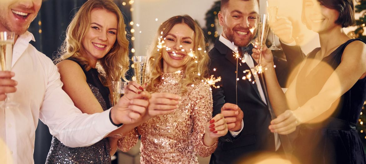 With sparklers in hands. Group of people have a new year party indoors together.