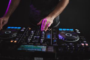 Closeup of a DJ working under the colorful lights in a studio with a blurry background