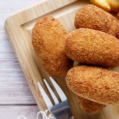 Homemade croquettes with chips on wood cutting board